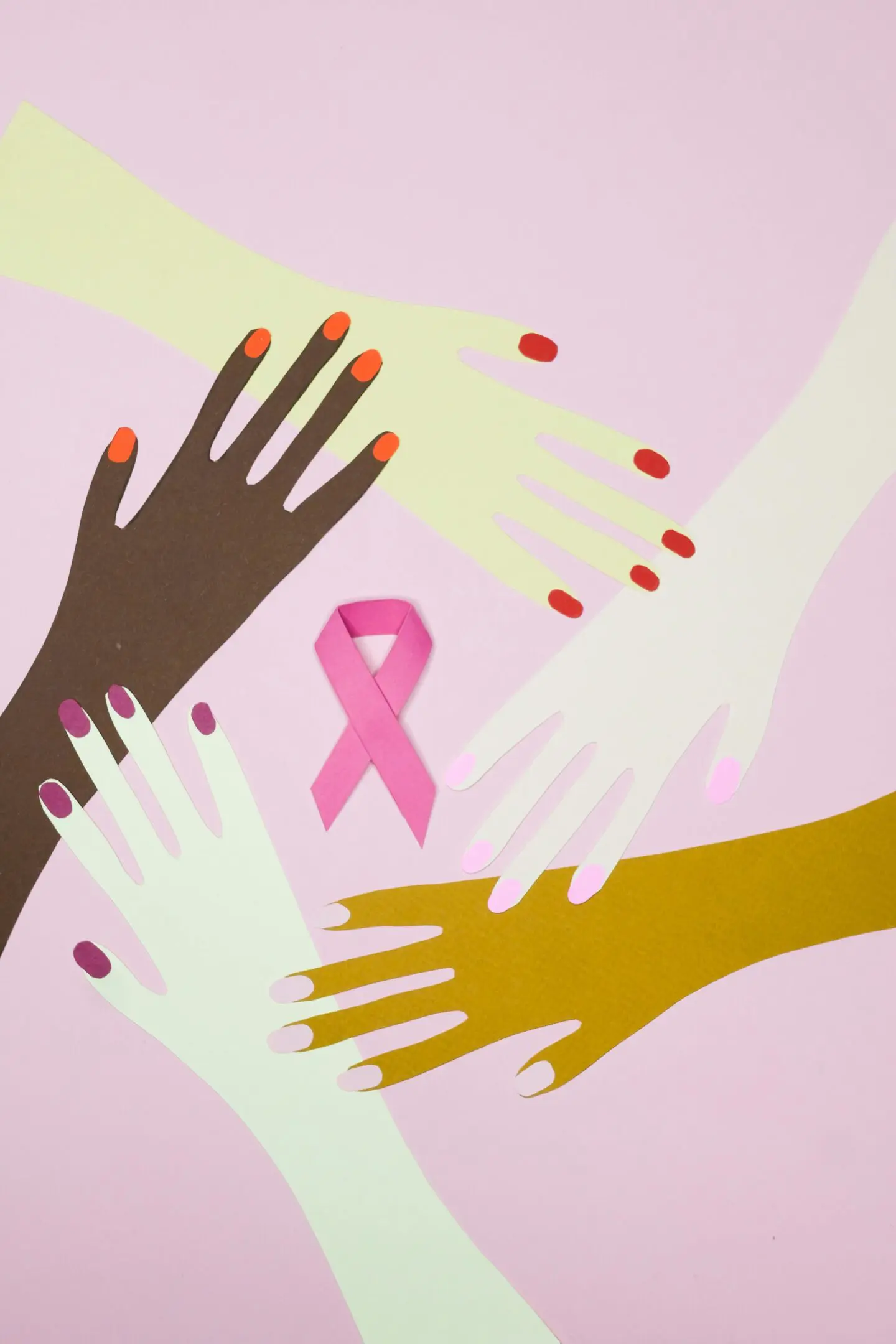 Diverse hands surrounding a pink breast cancer awareness ribbon.