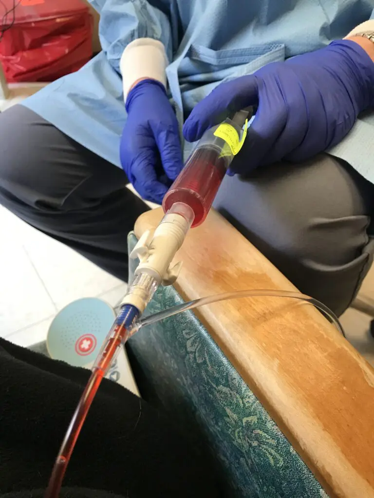 A medical professional drawing blood from a patient's arm.