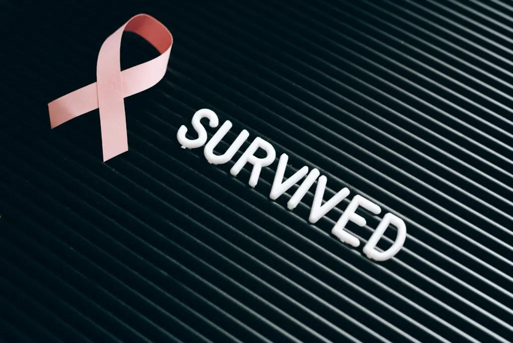 Pink ribbon with the word 'SURVIVED' symbolizing breast cancer survival.