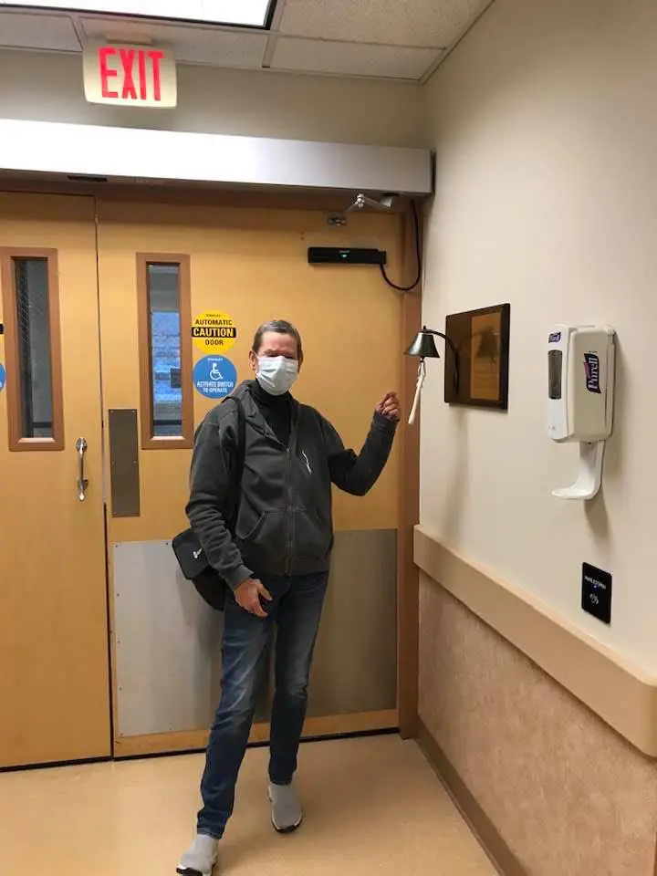 Person wearing a mask pressing a button on a hospital wall.
